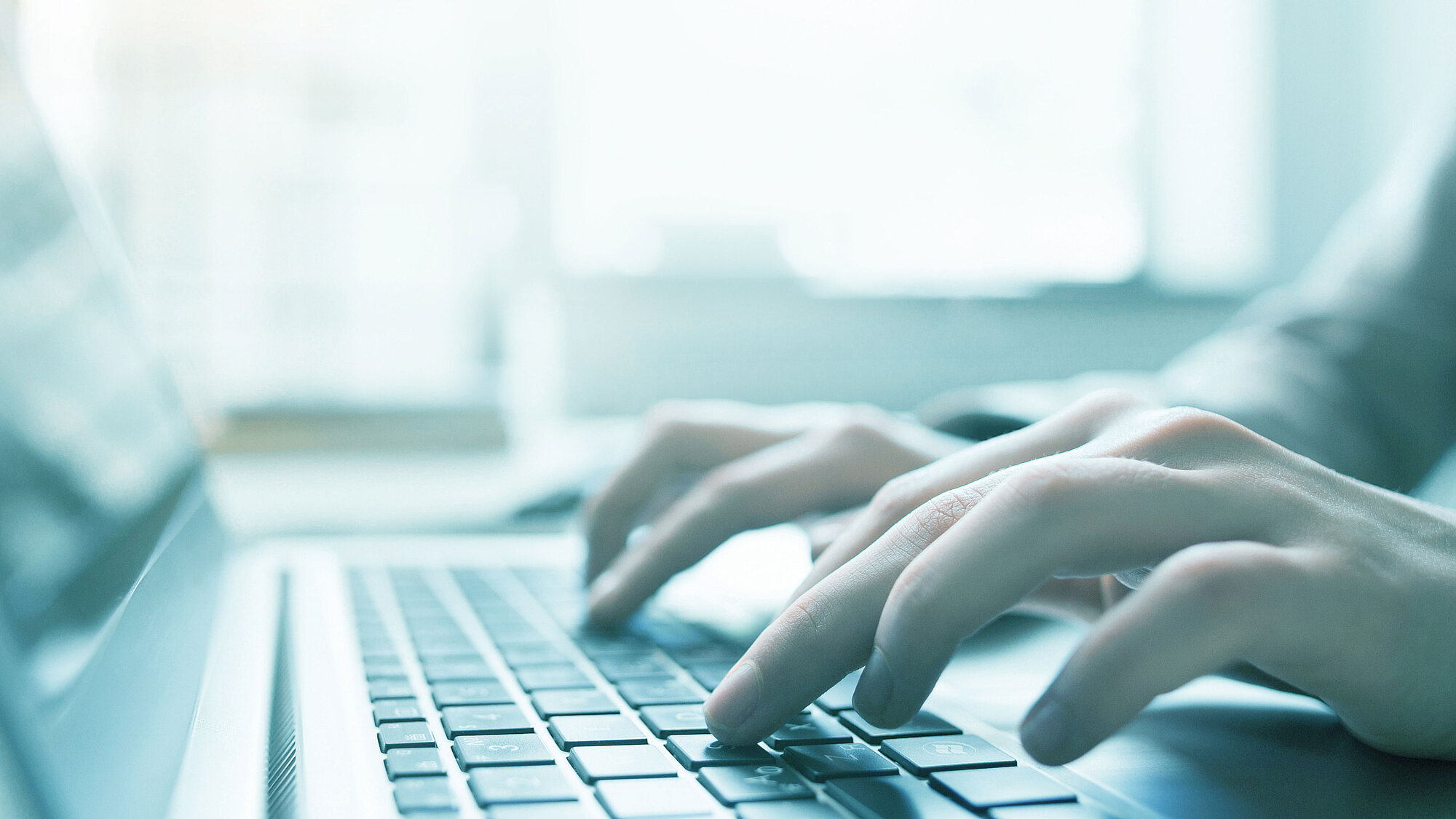 One person working at a computer, you can see only hands and keyboard