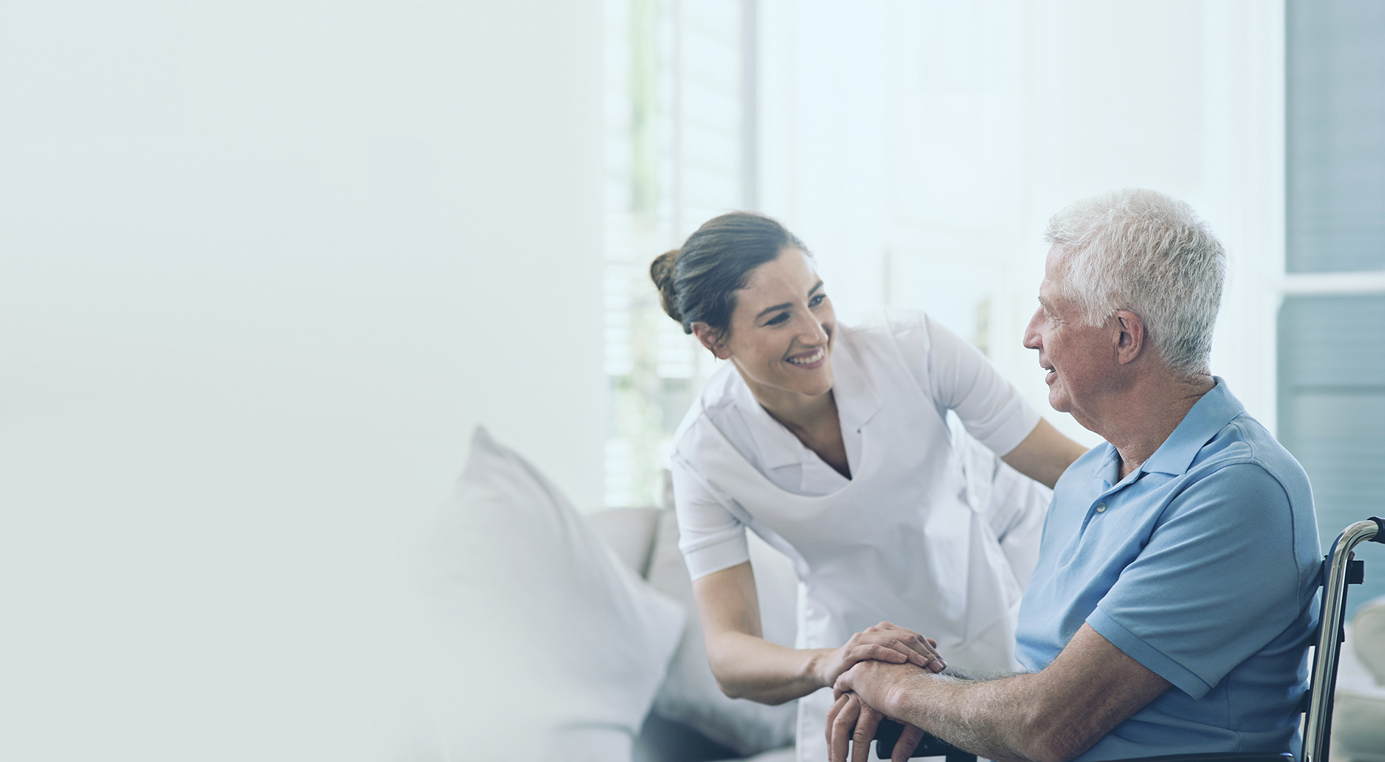 A nurse kindly cares for an elderly man in a wheelchair